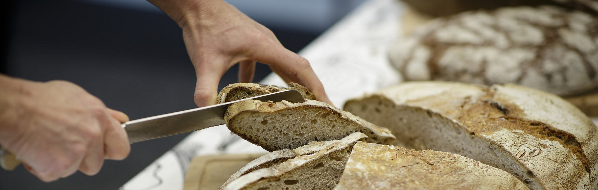 Brot wird in Scheiben geschnitten im Rahmen einer Ich kann kochen! Veranstaltung.