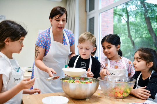 Kinder bereiten mit Genussbotschafterin Salat zu.